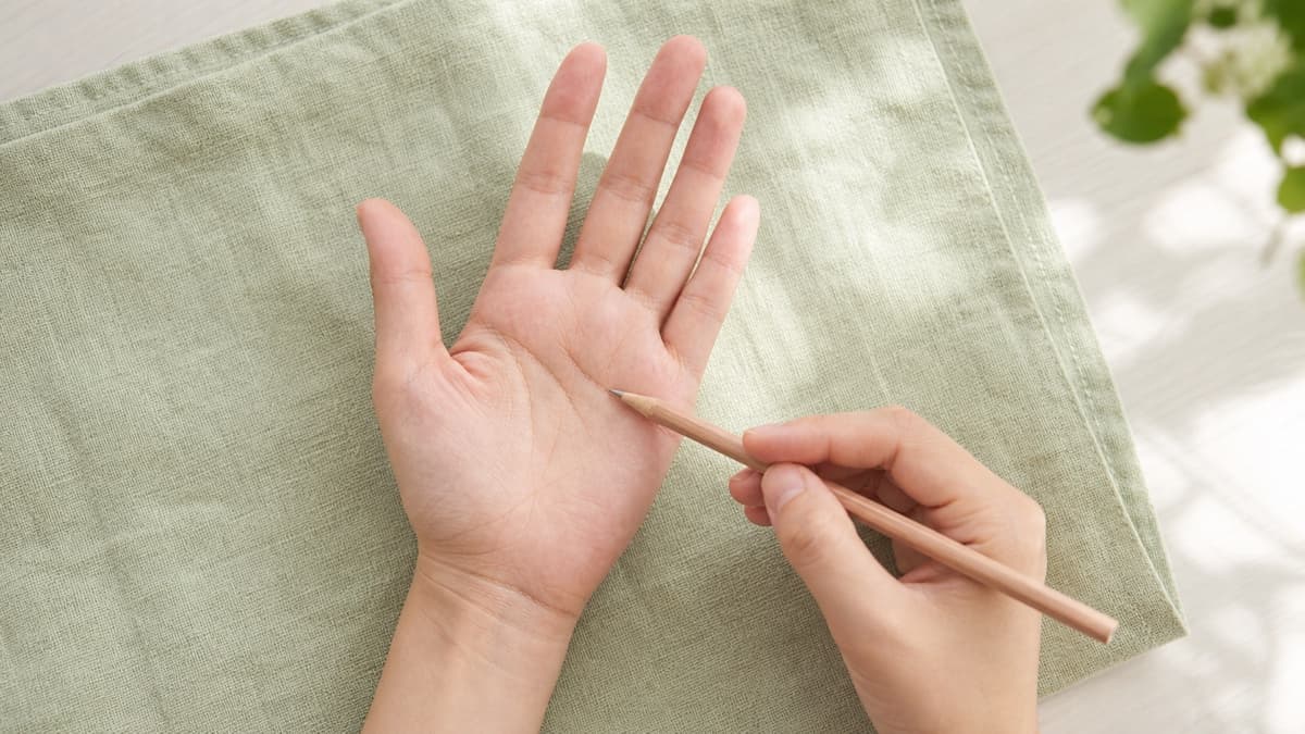 明るい机の上で手のひら中央を通る知能線を観察している様子