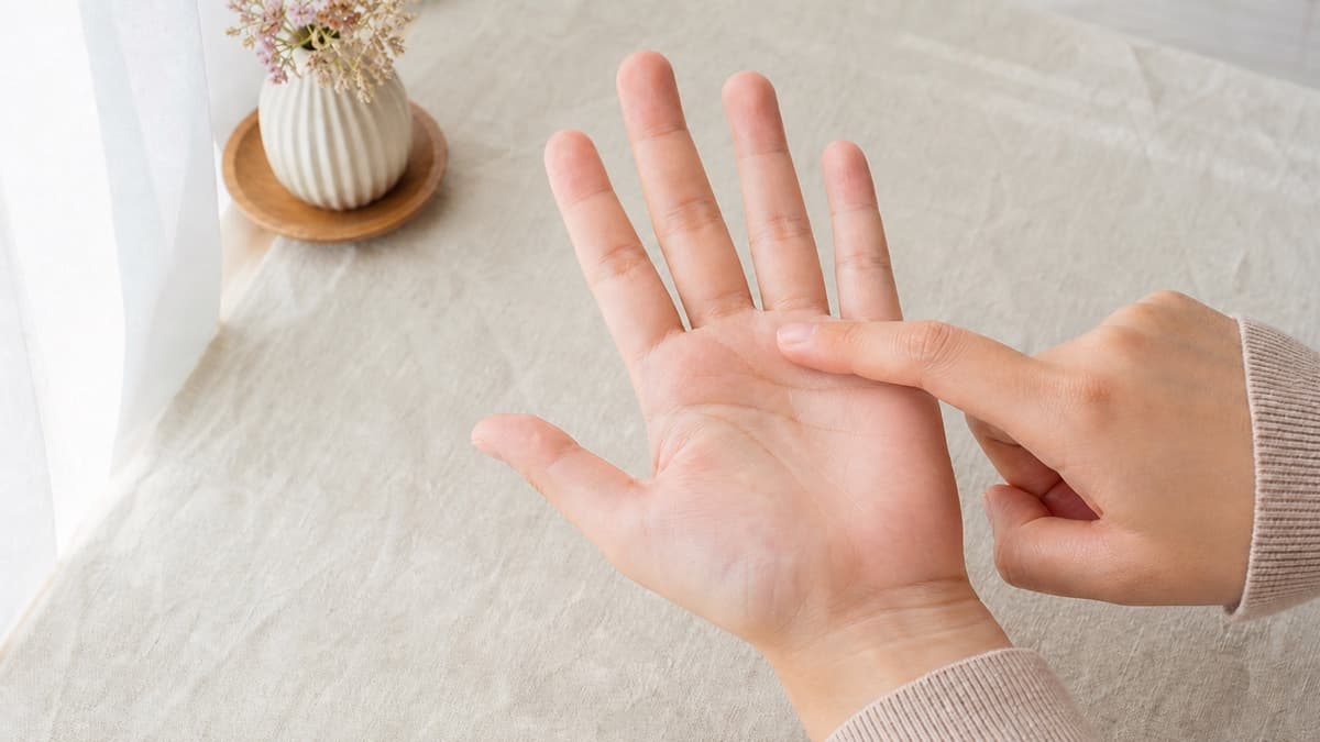 自然光の下で手のひら上部の感情線を指先で確かめている様子