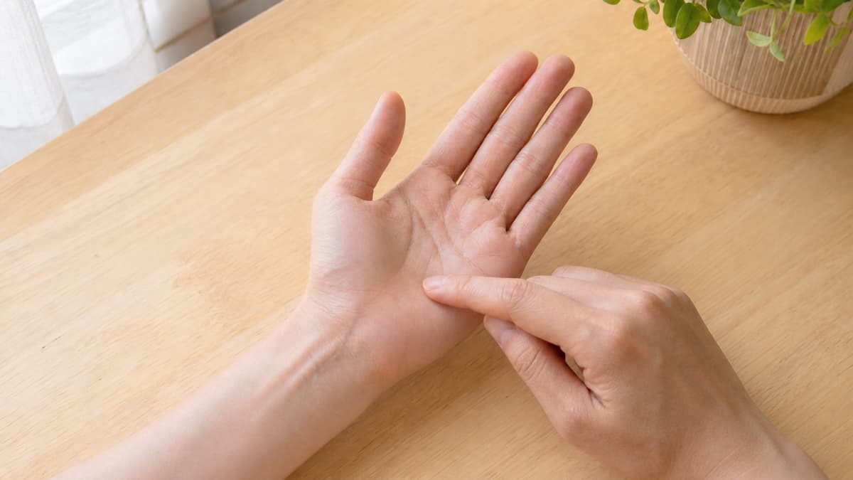 自然光の下で親指の付け根を囲む生命線のカーブを観察している様子