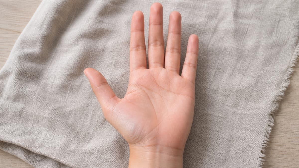 自然光の下で手のひらの主要線が中央付近で薄く途切れて見える部分を確認している様子