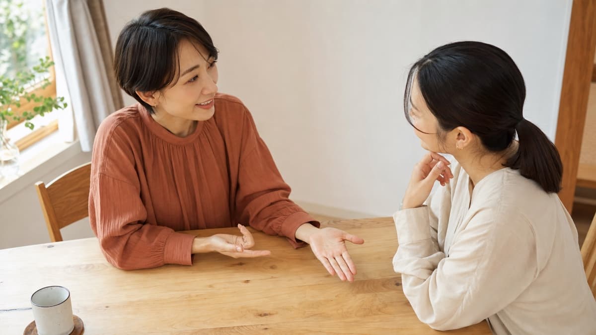 明るいテーブルを囲み、開いた手のひらを見ながら友人同士で穏やかに会話する様子