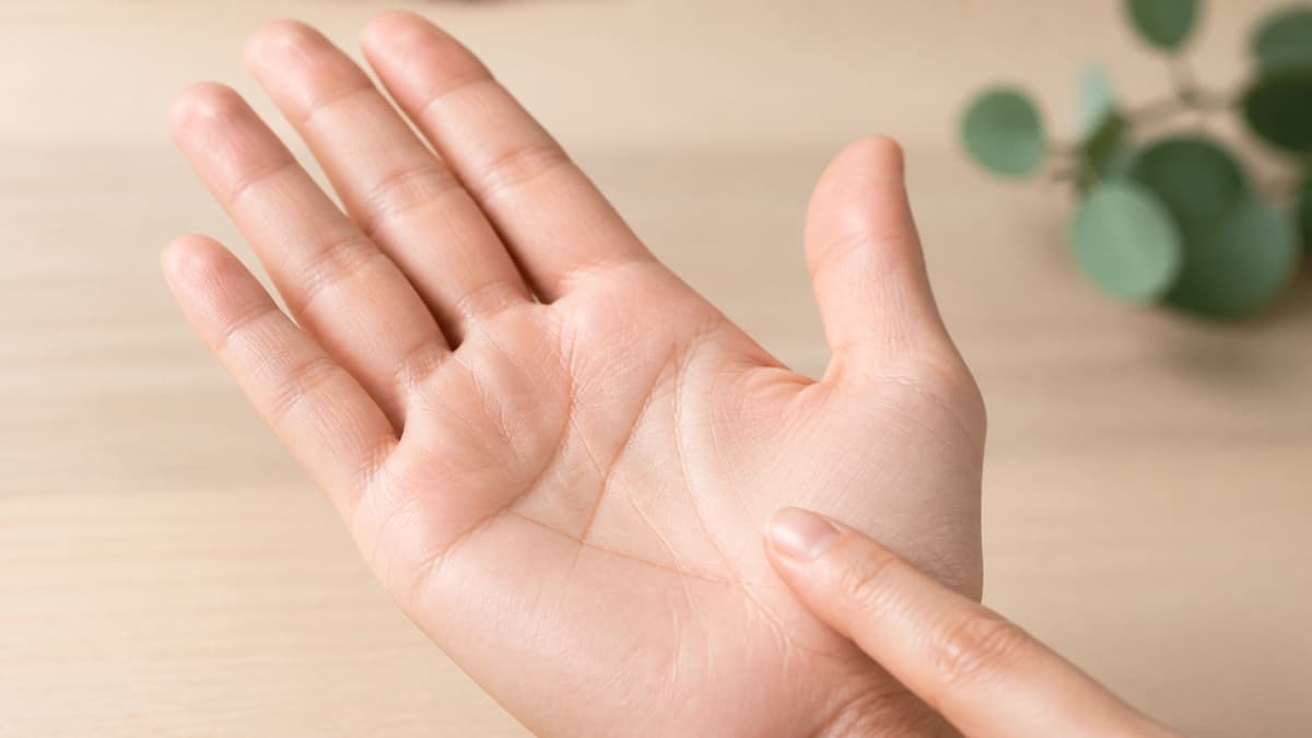 自然光の下で手のひらに見える小さな三角形の線を指先で確認している様子